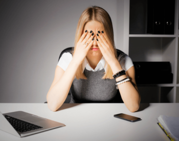 Lowering Stress Hormone Cortisol Naturally, Here’s How Woman sitting at desk looking stressed out